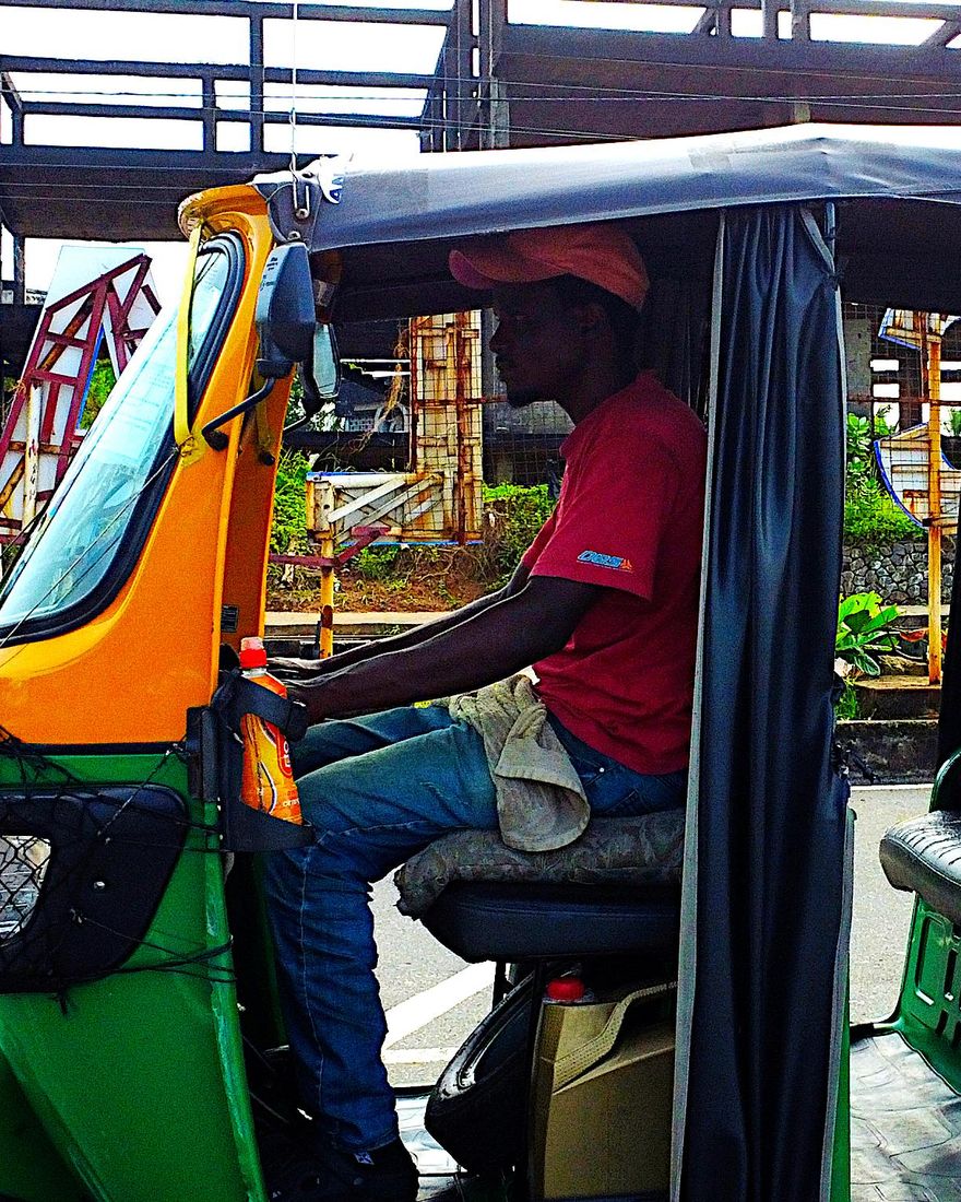 A green and orange kekeh, the three-wheeled taxi of the Kekeh Tour, with its driver